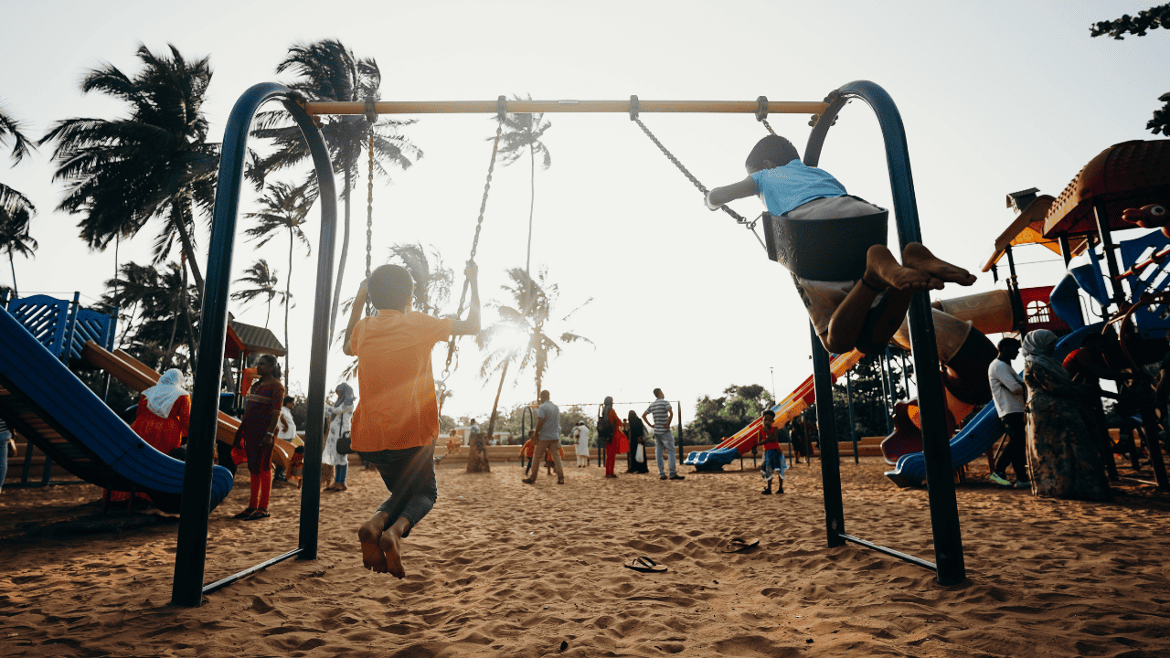 Kids playing on the swing set on a playground.